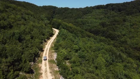 Aufsteigende-Antenne-Eines-4x4-Autos,-Das-Von-Der-Straße-In-Den-Wald-Fährt