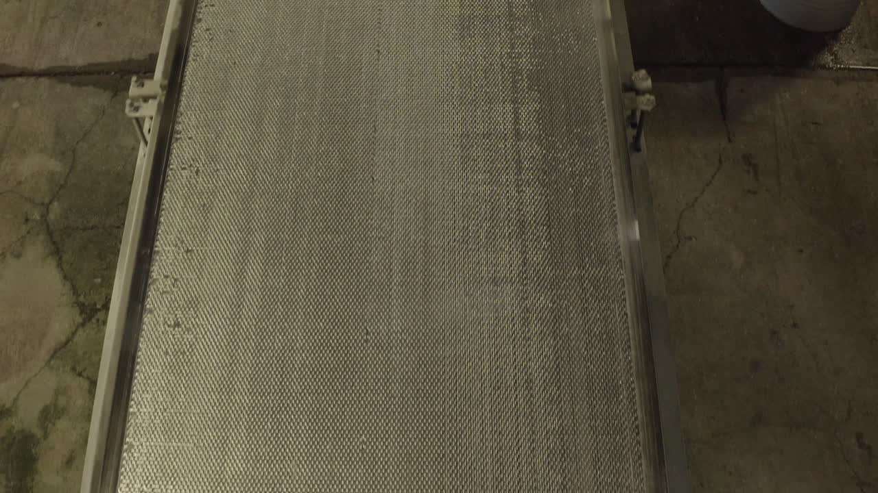 Close-up of textured industrial conveyor belt moving, likely for sorting or processing, Veille-Saint-Girons, France