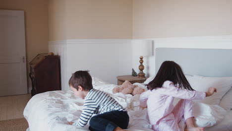 niños divirtiéndose saltando y jugando en la cama de los padres en casa