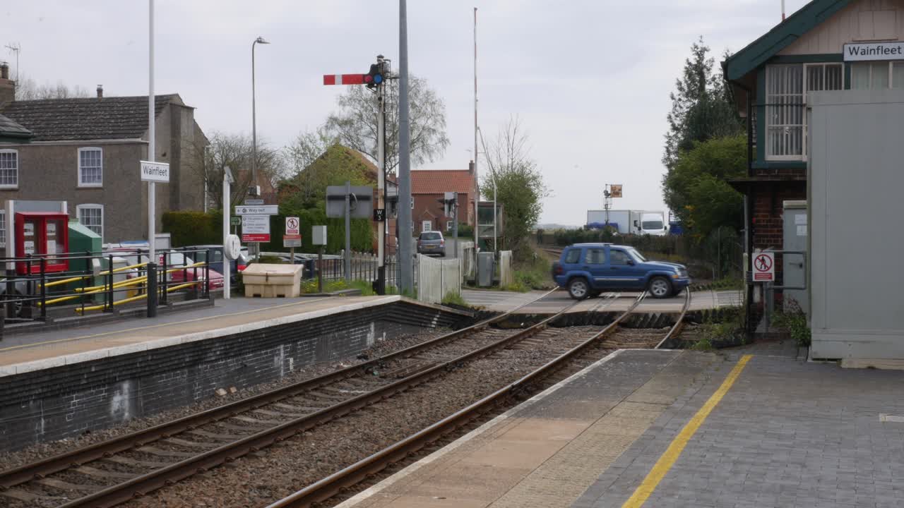 coches cruzando las vías del tren en una antigua estación de tren de pueblo en inglaterra