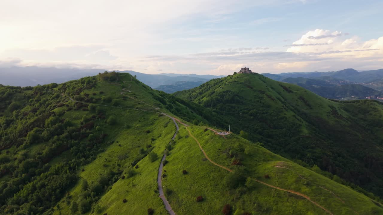 Ancient fort on a green Italian hill with forest trails under a calm sky