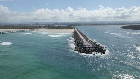 boats entering the nerang river - the spit and sand bypass pumping jetty at summer in qld, australia