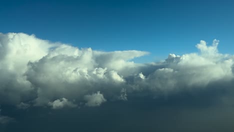 pov flying through stormy skies: a pilot’s perspective from an airplane cockpit flying at cruise with threatening cumulonimbus ahead in a deep blue sky. 4k 60fps