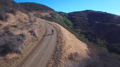 Buena-Toma-Aérea-Siguiente-De-Un-Ciclista-De-Montaña-Bajando-Rápidamente-Una-Montaña