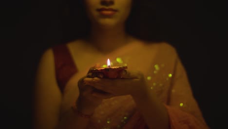 close up of woman celebrating festival of diwali holding lit diya oil lamp