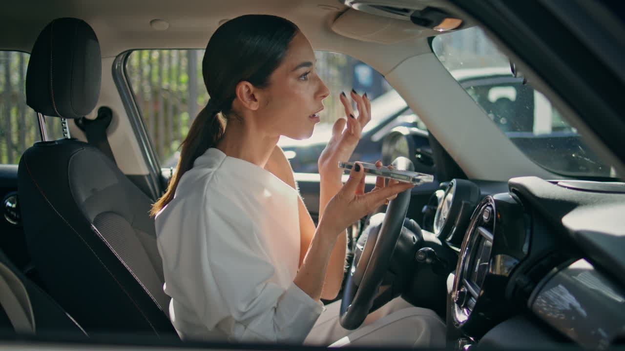 Beautiful girl sending voice message sitting expensive automobile close up.