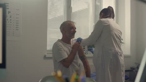 woman doctor preparing patient shoulder to injecting vaccine in modern hospital.