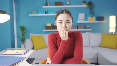 아시아 여성이 노트북에서 보는 것에 대해 걱정하는 표정으로 카메라를 쳐다보고 있습니다.