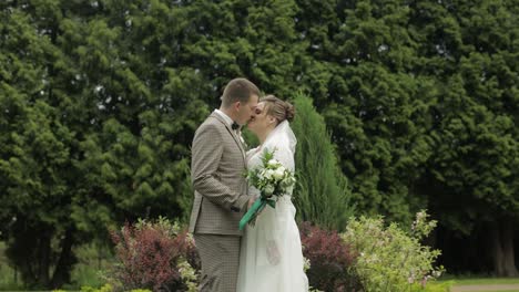 Newlyweds.-Caucasian-groom-with-bride-kissing-in-park.-Wedding-couple.-Man-and-woman-in-love