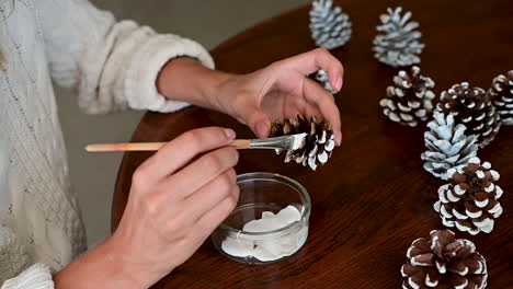 Female-Hands-Tie-The-Rope-Of-A-Gift-Box-With-Wrapping-Decorated-With-A-Pine-Branch-And-Snowflakes