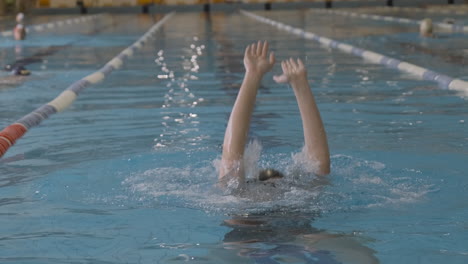 female swimmer doing immersion exercises in an indoor swimming pool