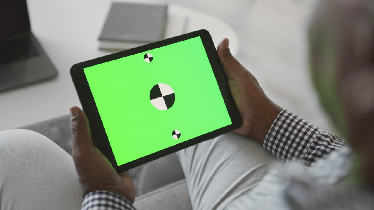 Older man holding a tablet with a green screen