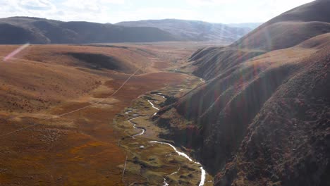 Cinematic-drone-dolly-tilt-up-of-meandering-river-at-base-of-valley,-Tibetan-Sichuan-grasslands