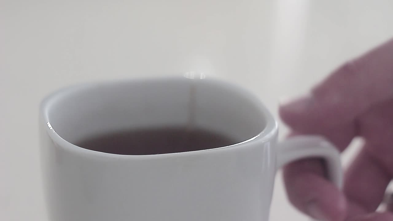 Man do some tea in a morning before he go to work! The cup stands on a desk and he put the tea bag in a cup! Then he pours the cup with a boiled water and waiting for tea been done!