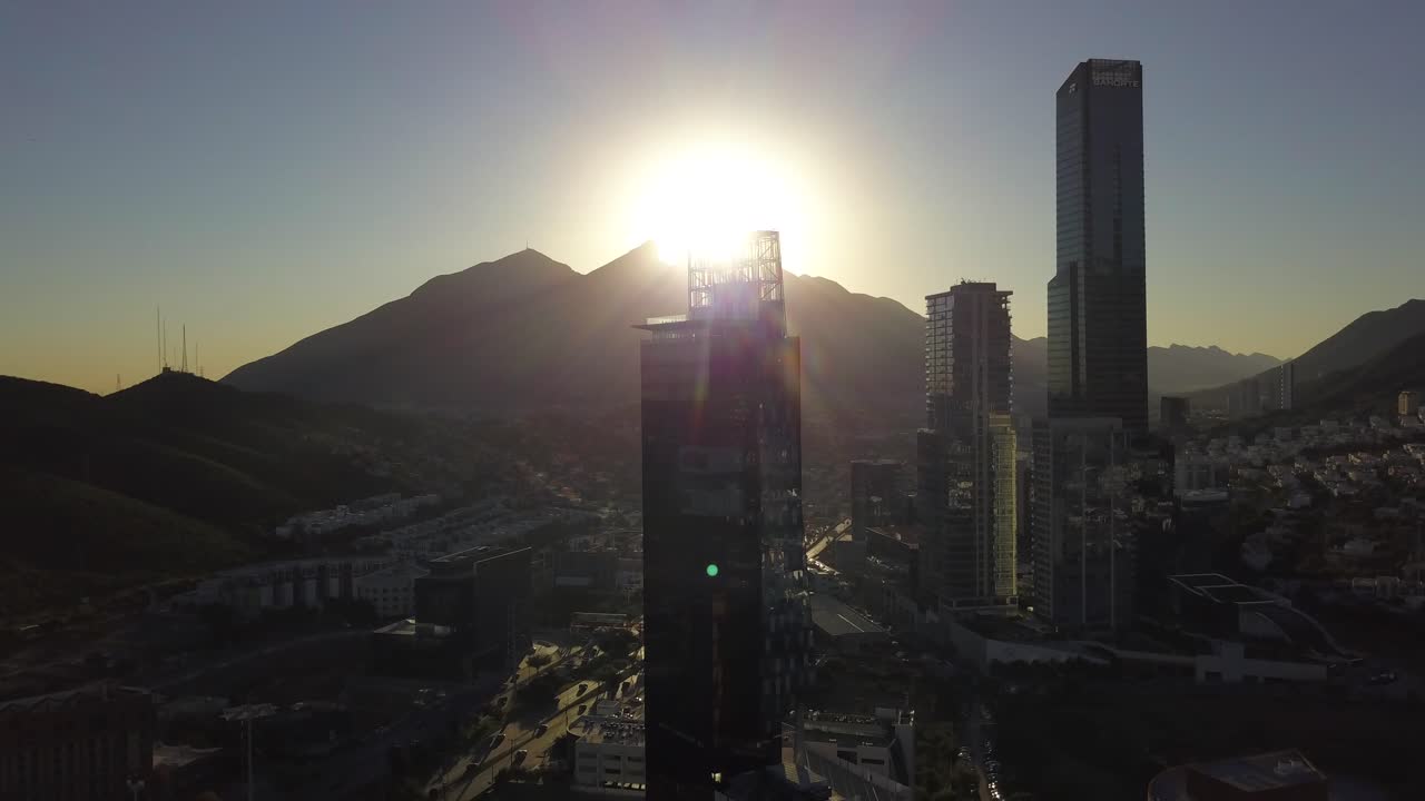 Tomada aérea de drone com elevação e afastamento, mostrando o nascer do sol no Cerro de la Silla com o horizonte de San Pedro