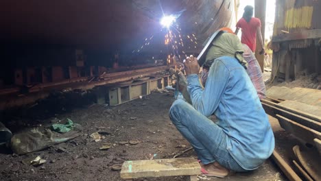 Welder-welding-ship-hull-at-a-dry-dock-shipyard