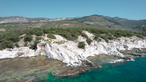 aerial side view of aliki ancient marble quarry with turquoise water and large white pieces of marble, thassos, greece