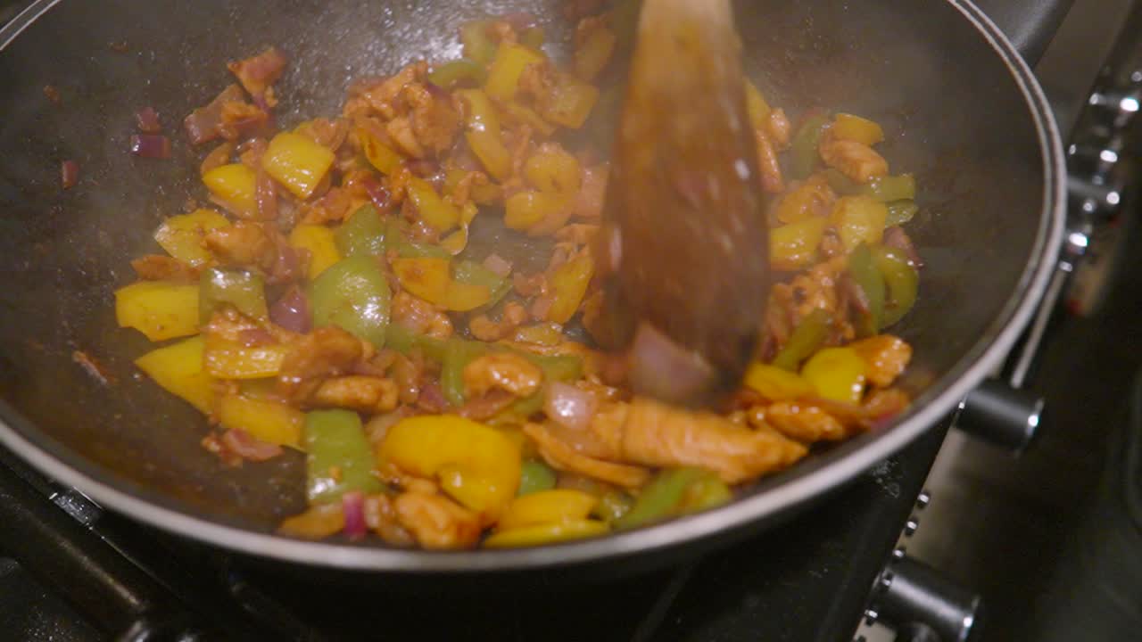 Ultra Slow Motion of Chicken and Vegetables Cooked on High Heat in Wok to Make Spicy Mexican Fajitas Mix Ready to Load in Tortillas with Salsa and Salad.