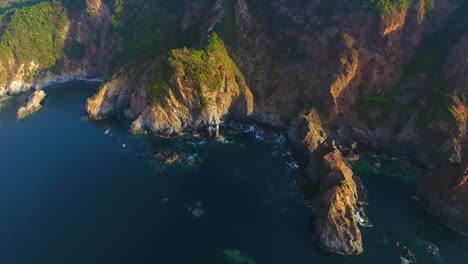 a drone view panning over the rough mountainous coast of carrizal anchorage near mexico during golden hour in summer