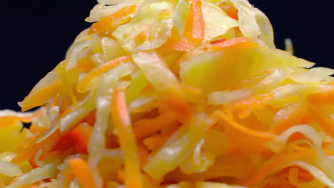 색 접시 위에 신선한 채소 러드가 검은색 배경에 회전합니다.