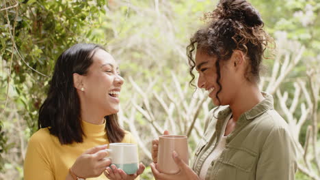 sharing laughter and friendship, two multiracial female friends drinking coffee on porch together
