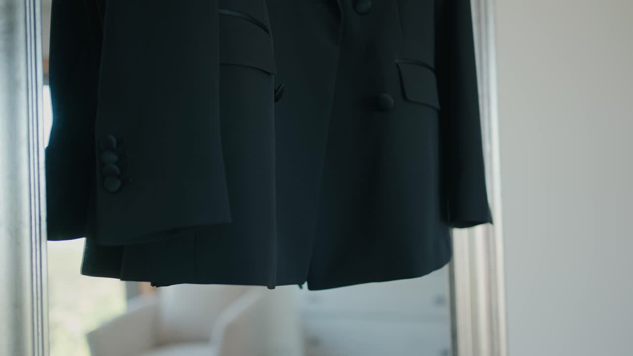 Close up of a black suit jacket hanging neatly on a hanger ready for a formal event