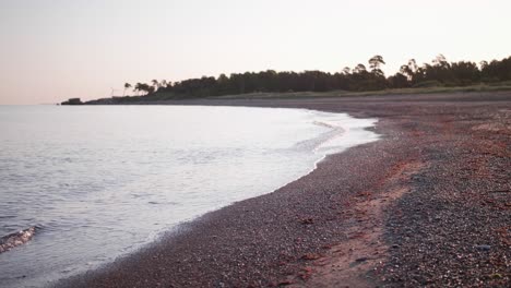 A-calm-seashore-scene-with-small-waves-and-small-rocks-in-the-foreground