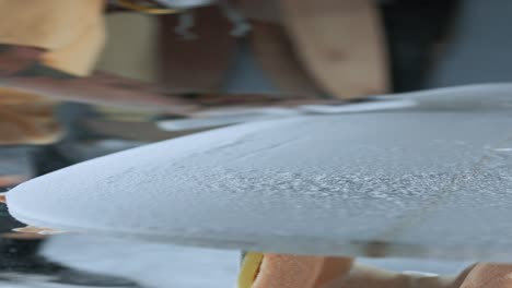 unrecognizable man polishing surfboard with special tool