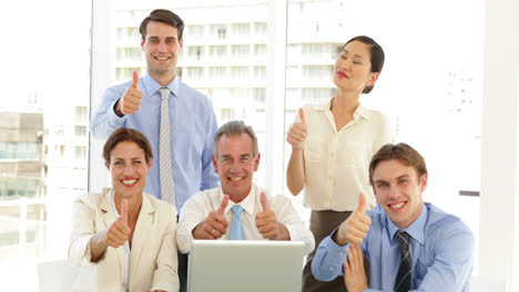 Happy-business-team-posing-in-front-of-laptop