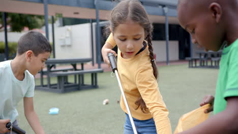 in school, children cleaning up playground using grabbers and trash bags