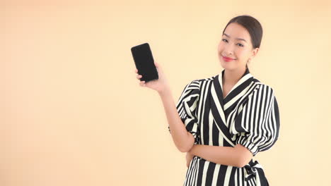 an attractive, sassy, young woman dressed in a zebra print dress raises her smartphone and smiles