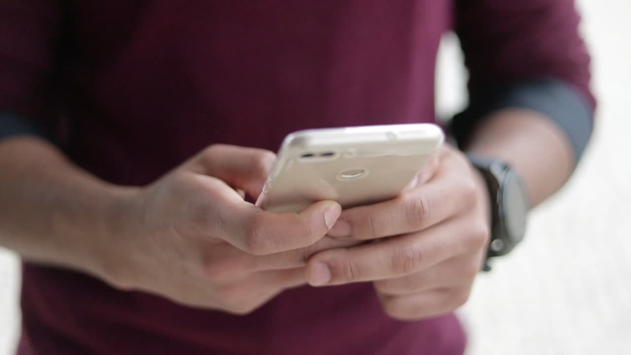 una foto de cerca de manos masculinas de raza mixta enviando mensajes de texto por teléfono