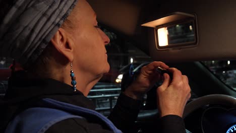 Close-up-view-of-a-woman-putting-lipstick-on-in-a-parking-lot,-sideways