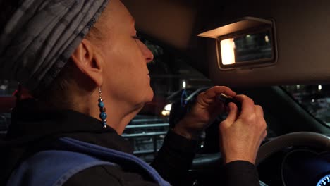 close up view of a woman putting lipstick on in a parking lot, sideways