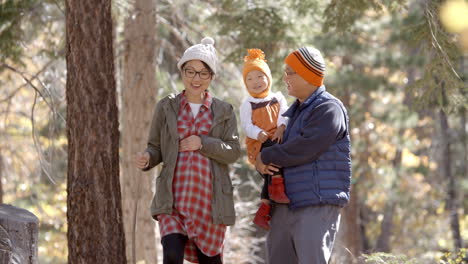 pregnant asian mother, husband and daughter hiking in forest