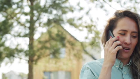 mujer sosteniendo café y hablando por teléfono al aire libre