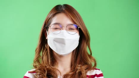 크로마 키 배경으로 스튜디오 녹음 중 카메라를 바라보는 보호 마스크를 쓴 아시아 젊은 여성