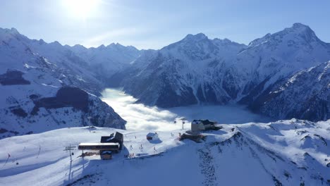 una vista de drones de una estación de esquí por encima de las nubes en un día soleado en las altas montañas nevadas