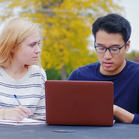 Los-Estudiantes-Trabajan-Con-Una-Computadora-Portátil-En-La-Mesa-De-Un-Café-De-Verano-1