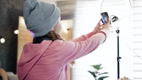 female vlogger adjusts the mobile phone  angle in ring light with during broadcast or live streaming