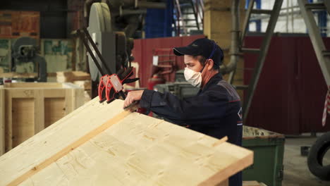 trabajador que ensambla tablas de madera en una fábrica