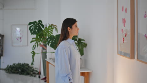 woman watching art paintings in museum. thoughtful visitor looking exhibition