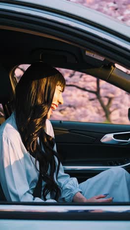 woman driving through cherry blossom trees at sunset