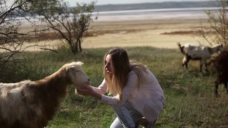 woman stroking goat outdoors closly watching to goat face