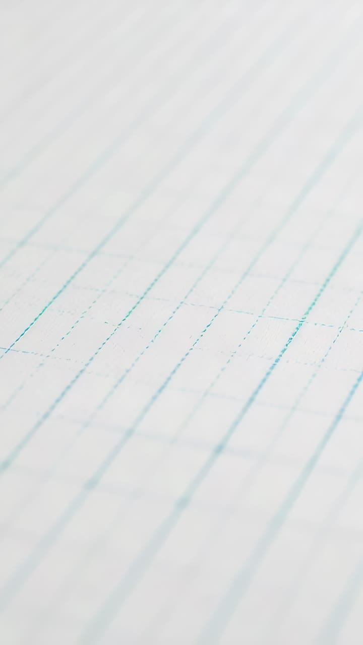 Vertical video: Shifting camera slightly, revealing diagonal ruled paper on desk with blue lines