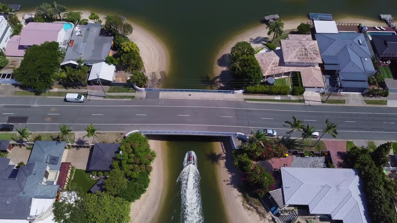 Aerial drone birds-eye shot tracking jetski through bridge underpass in Broadbeach Waters, Gold Coast