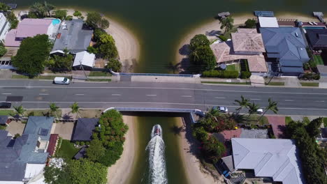 aerial drone birds-eye shot tracking jetski through bridge underpass in broadbeach waters, gold coast