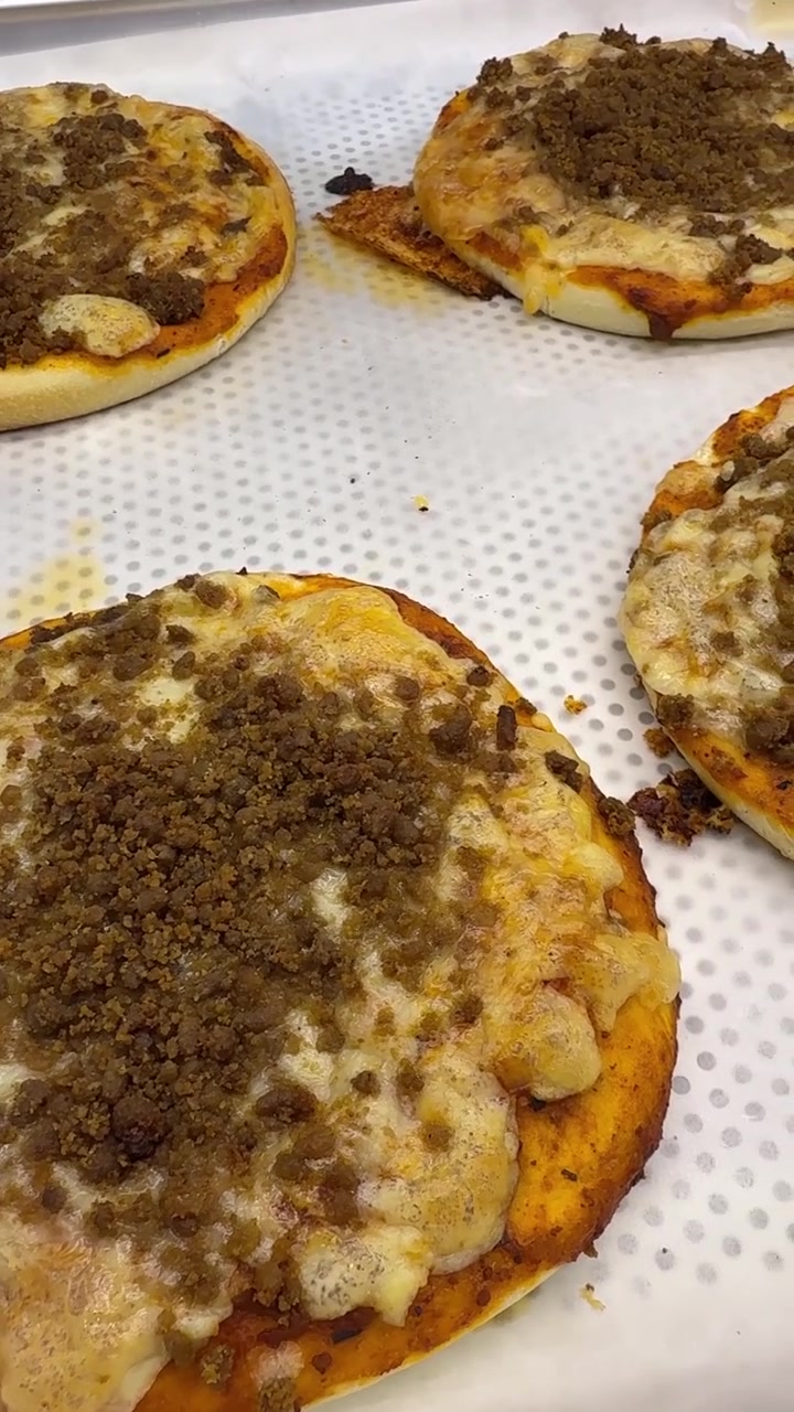 Mini pizze appena sfornate con condimento di carne macinata su teglia da forno