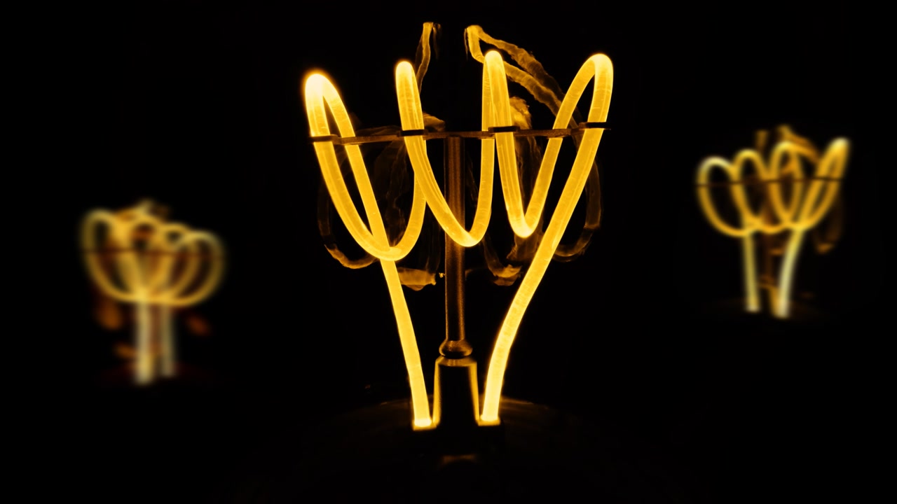 Lampade a incandescenza al tungsteno tremolanti con una spirale arancione macro. Lampada a spirale incandescente in primo piano su sfondo nero. Loop video raw 4k