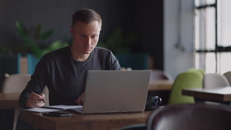 Smiling man with works from home in his kitchen using a laptop. Remote work and remote learning. remote work during self-isolation in quarantine man works with financial documents.